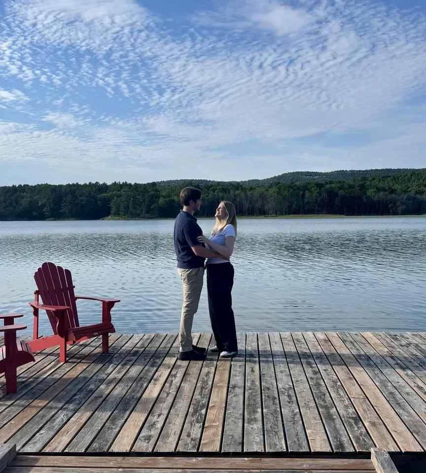 Saskia and Eli standing together on a dock after the proposal